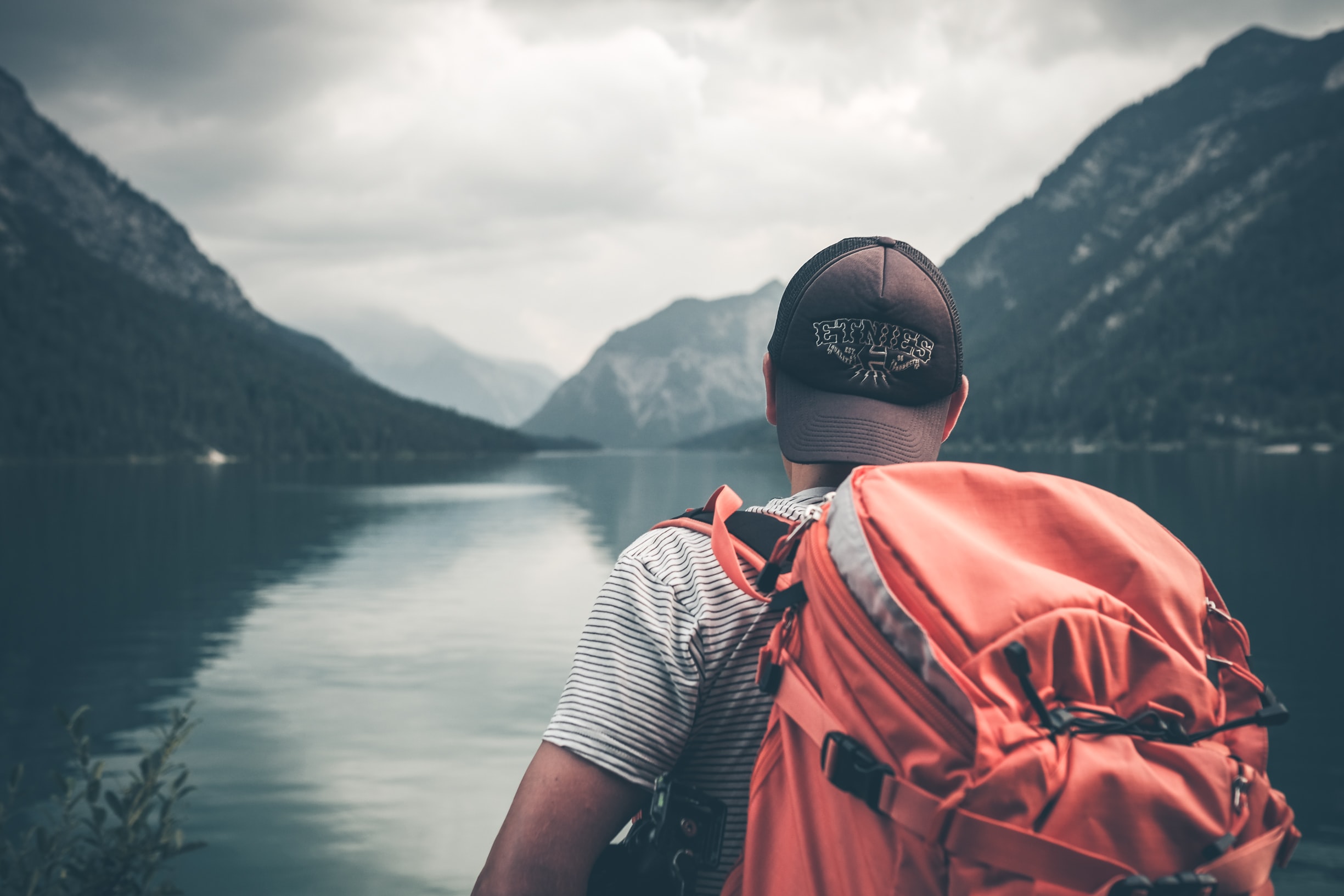 man looking at a lake with bagpack on